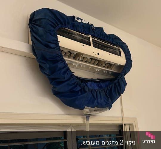 מזגן עם כיסוי כחול לתחזוקה על קיר